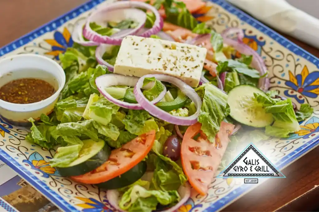 Greek salad with feta cheese, cucumbers, tomatoes, and onions on a decorative plate.