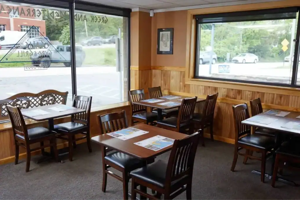 Cozy Greek restaurant dining area with wooden tables and chairs.